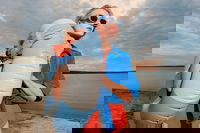 A girl on the beach wearing sunglasses and holding an swim ring in her hands